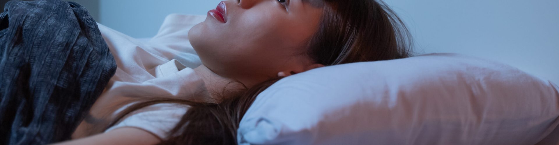 Asian women opened eyes lying on the bed have an insomnia problems.